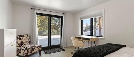 A modern bedroom with a bed, a desk, a chair, and a wardrobe.