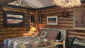 Une chambre de style rustique, aménagée comme un chalet, avec un lit en bois, une table et un luminaire suspendu.
