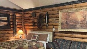 Une pièce confortable, aménagée dans le style d’un chalet, avec un lit en bois, un canapé, une table et un tableau au mur.