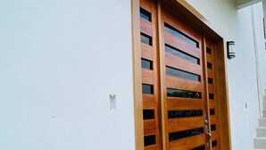 Ein moderner Gebäudeeingang mit einer großen Holztür und zwei Wandleuchten.