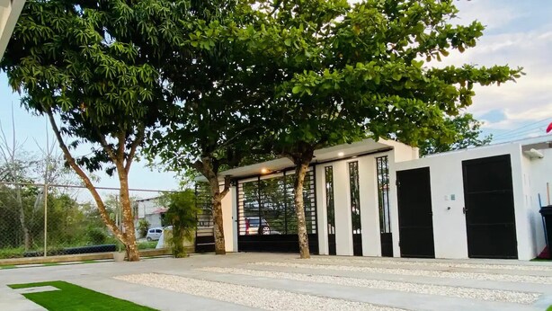 A modern building with a gated entrance, a paved driveway, and a well-maintained lawn.