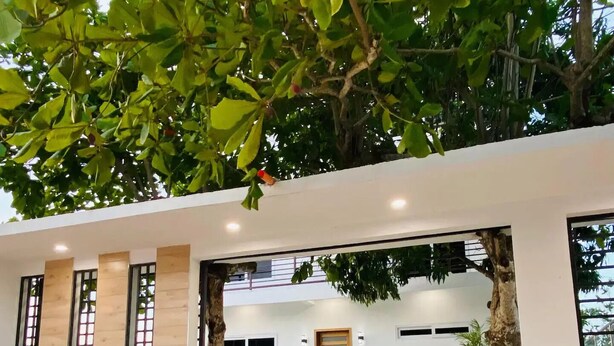 A modern building with large windows, a concrete entrance, and a gravel driveway. - Casa Victoria 1 (Flores)