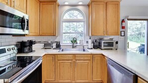 Une cuisine moderne avec des meubles en bois, des appareils électroménagers en acier inoxydable et une grande fenêtre qui laisse entrer la lumière naturelle.
