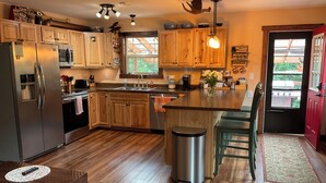 Une cuisine moderne avec des meubles en bois, des appareils électroménagers en acier inoxydable et un îlot central doté de tabourets de bar.