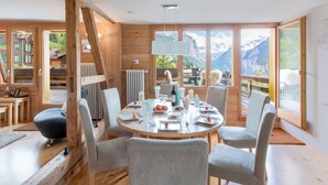 Un coin repas avec une table ronde, des chaises et une vue sur les montagnes.