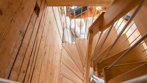 Un escalier en bois mène à une pièce où se trouvent un canapé blanc et un téléviseur.