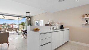 A modern kitchen with a central island, white cabinetry, and a view of the outdoors. - Casa Hermano - Private Pool Penthouse (Marbella)
