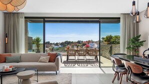 A modern living room with a sofa, coffee table, and dining area with chairs and a table. - Casa Hermano - Private Pool Penthouse (Marbella)