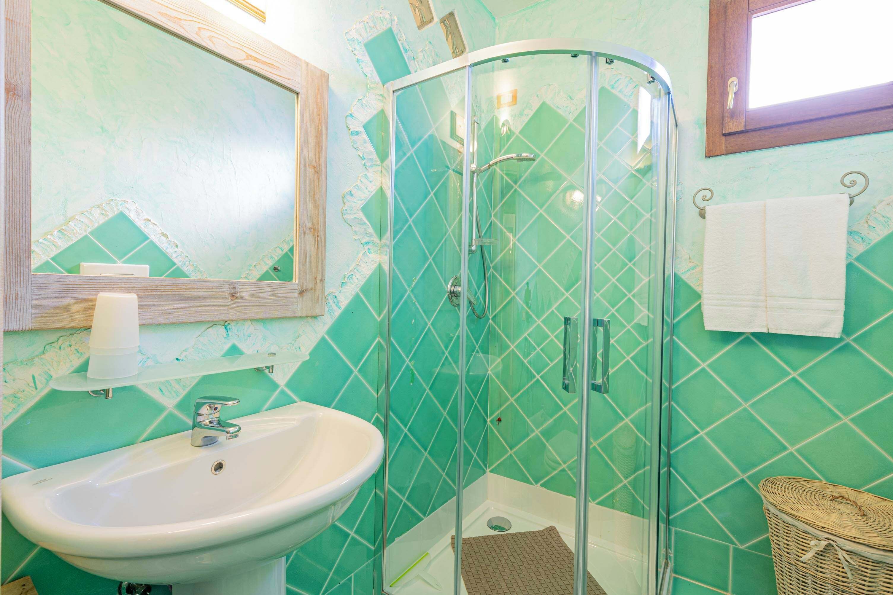 A bathroom with a glass-enclosed shower, a sink, and a mirror.