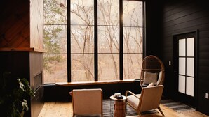 A cozy room with a large window, two chairs, a small table, and a plant.