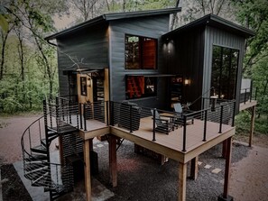 Eine moderne Holzhütte mit einer Holzterrasse, einer Wendeltreppe und einem Kamin.