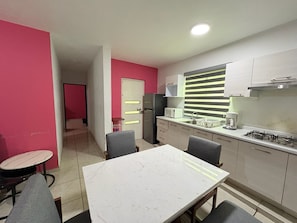 A compact kitchen with a dining area, a refrigerator, a microwave, and a gas stove. - Lomas Altas Tonala Céntrico 1 (Tonalá)