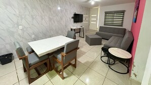 A living room with a dining table, chairs, a sofa, a small round table, and a ceiling fan.