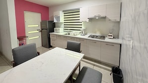 A compact kitchen with a dining area, a refrigerator, a microwave, a stove, and a sink.