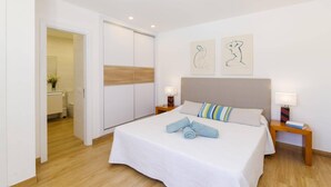 Een slaapkamer met een bed, twee nachtkastjes, een kledingkast en twee abstracte kunstwerken aan de muur.