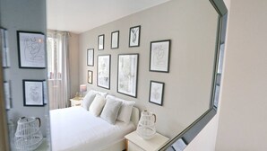 Ein Schlafzimmer mit einem großen Bett, einem Nachttisch mit Lampe und einer Wand mit gerahmten Kunstwerken.