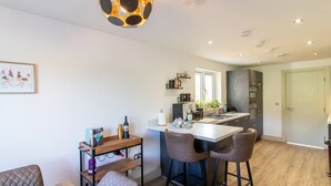 Cozinha moderna com ilha central, banquetas e luminária pendente.