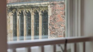 A view through a window with a metal grille and stone arches, part of a brick building. - 4, 35 Fossgate · Cosy Central 2-Bed Home Right in the Heart of York - Pass the Keys (York)