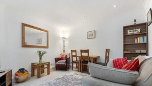 A living room with a sofa, chairs, a table, a bookshelf, a mirror, and a vase with flowers. - 4, 35 Fossgate · Cosy Central 2-Bed Home Right in the Heart of York - Pass the Keys (York)