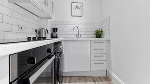 A modern kitchen with white cabinetry, a stainless steel sink, and a coffee maker. - 4, 35 Fossgate · Cosy Central 2-Bed Home Right in the Heart of York - Pass the Keys (York)