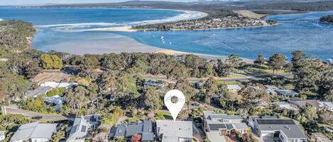 An aerial view of a coastal residential area with houses, a beach, and a marina.