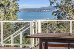 Un balcon avec vue sur l’océan et les collines.