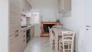 A compact kitchen with wooden cabinets, a built-in oven, and a dining area with a table and chairs.
