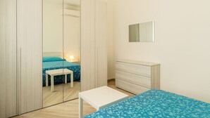 A bedroom with a bed, a bedside table, a dresser, and a wardrobe.