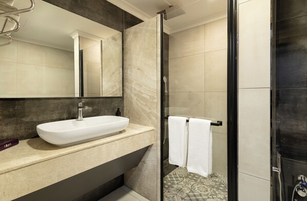 Une salle de bain moderne avec un grand miroir, un lavabo blanc et un espace douche.