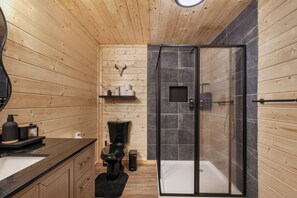A modern bathroom with wooden paneling, a black toilet, a glass shower enclosure, and a marble backsplash. - Smokies Pond Escape/Secluded Mtn cabin w/pond/Fish’n/Hot tub/2 fenced yards/Pets (Pigeon Forge)
