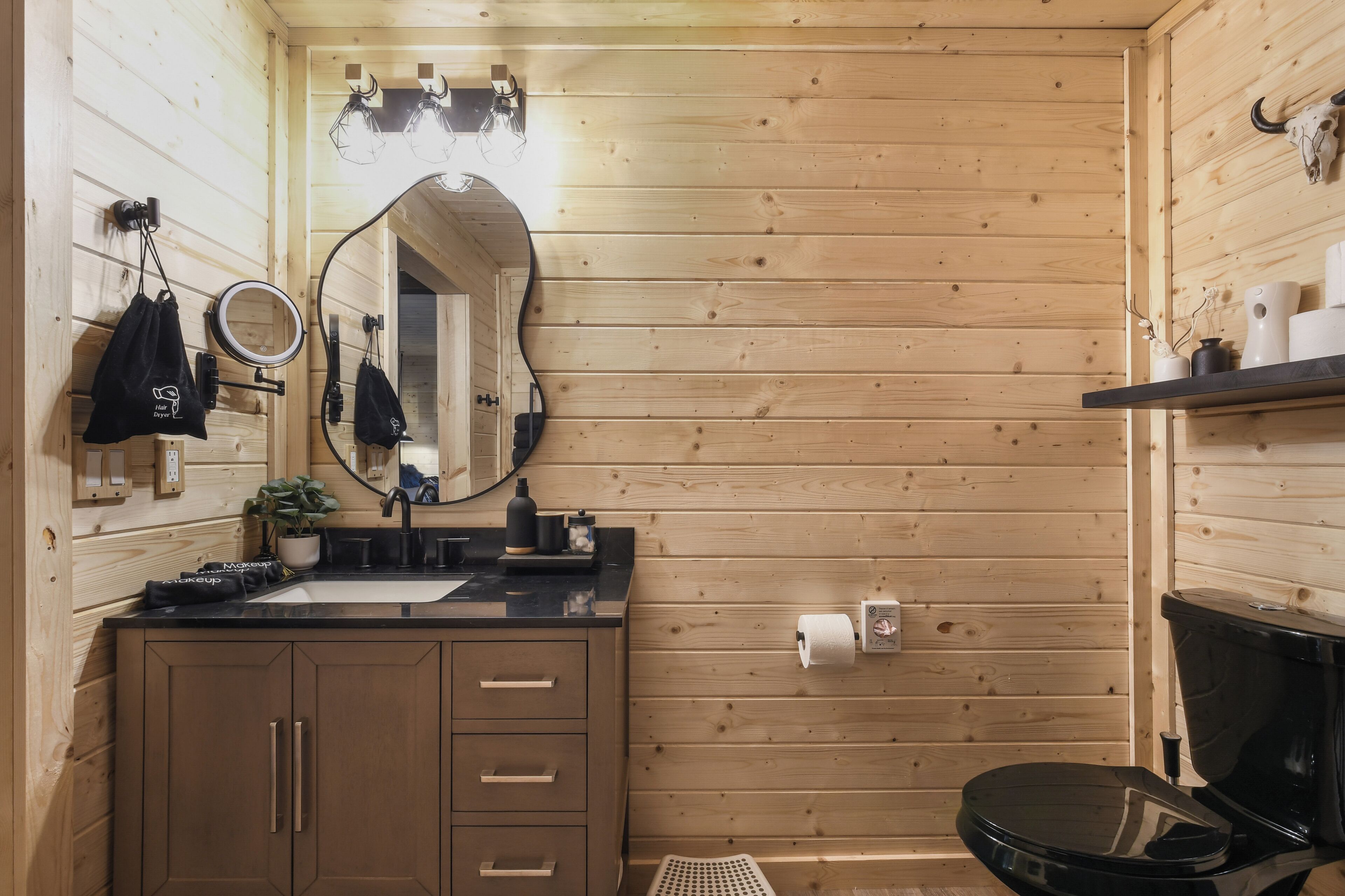 A wooden-paneled bathroom with a sink, mirror, and toilet.
