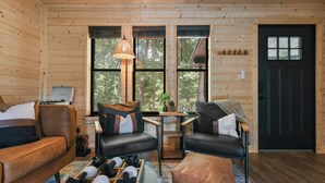 A cozy cabin interior with wooden walls, a black door, and a seating area with a sofa and a table. - Smokies Pond Escape/Secluded Mtn cabin w/pond/Fish’n/Hot tub/2 fenced yards/Pets (Pigeon Forge)