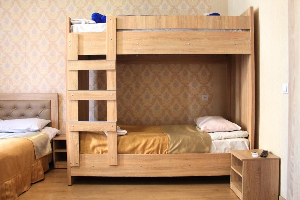 A bunk bed with a ladder, a bedside table, and a small shelf unit.