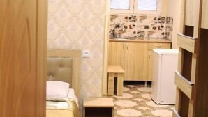 A compact room with a bed, a small kitchenette, and a wooden wardrobe. - Hotel WB (Kutaisi)