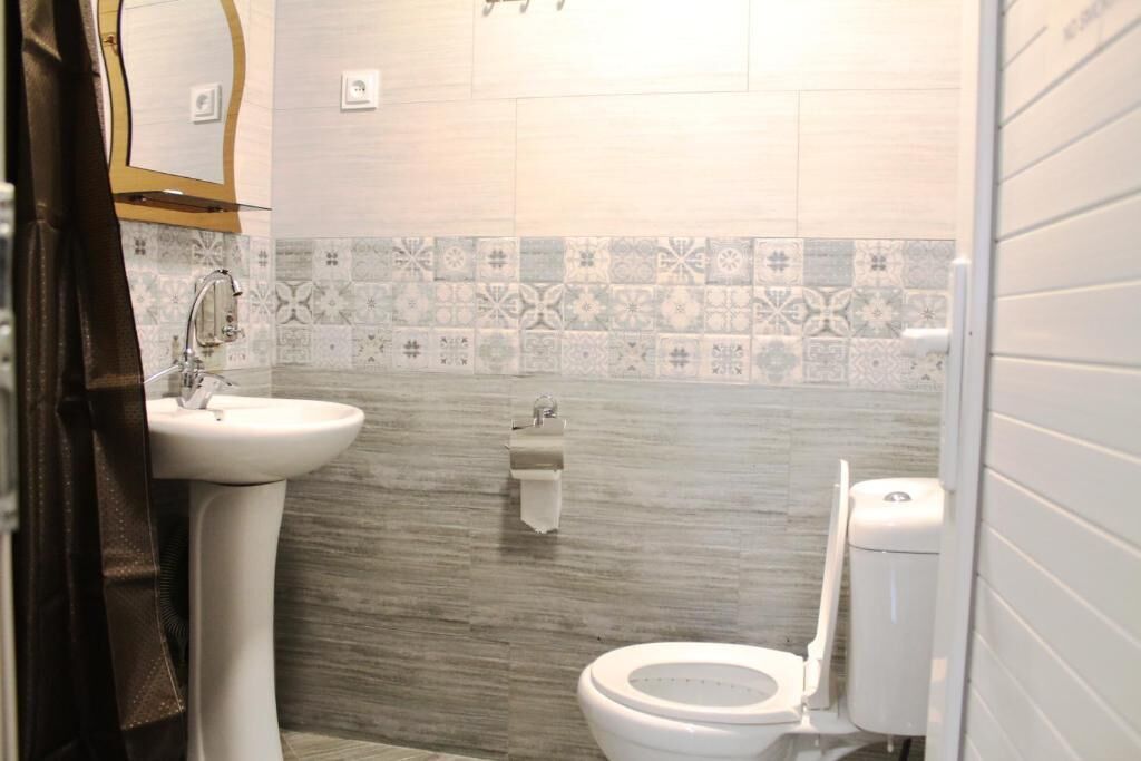 A bathroom with a sink, toilet, and decorative tiles.
