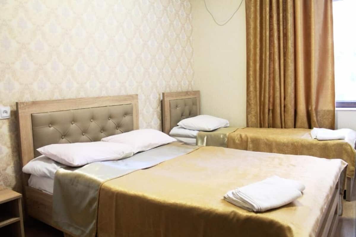 A hotel room with two beds, each with a tufted headboard and white bedding.
