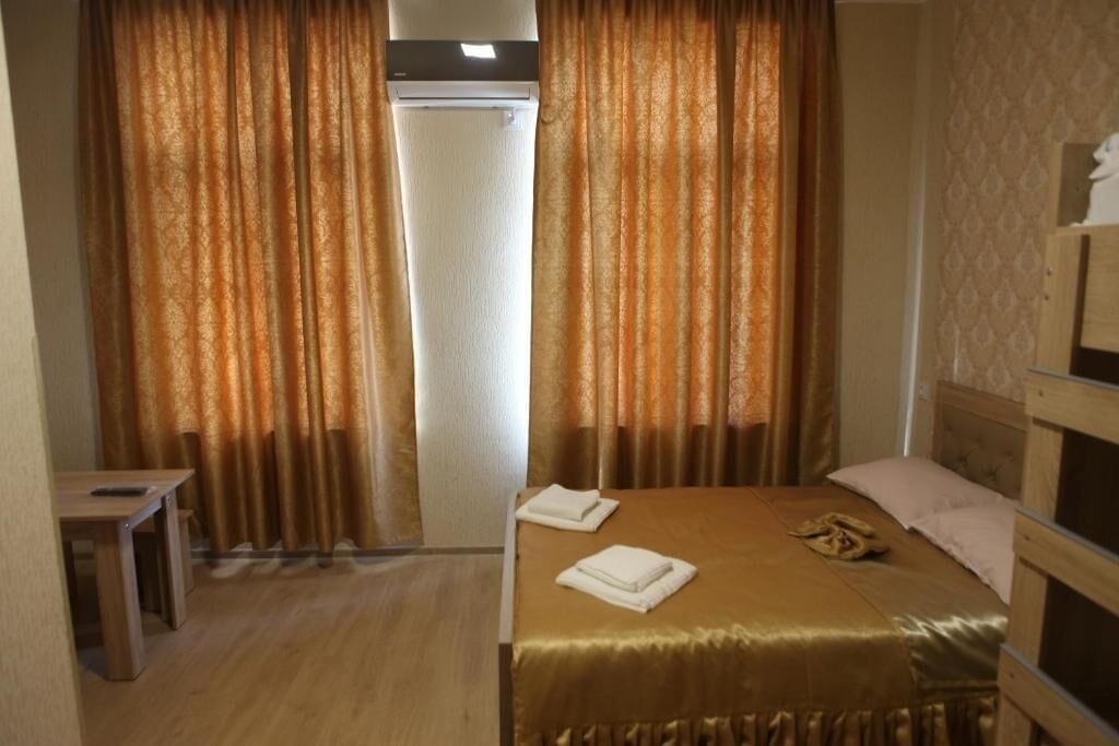 Une chambre d’hôtel avec un lit, une table de chevet, une lampe et des rideaux.