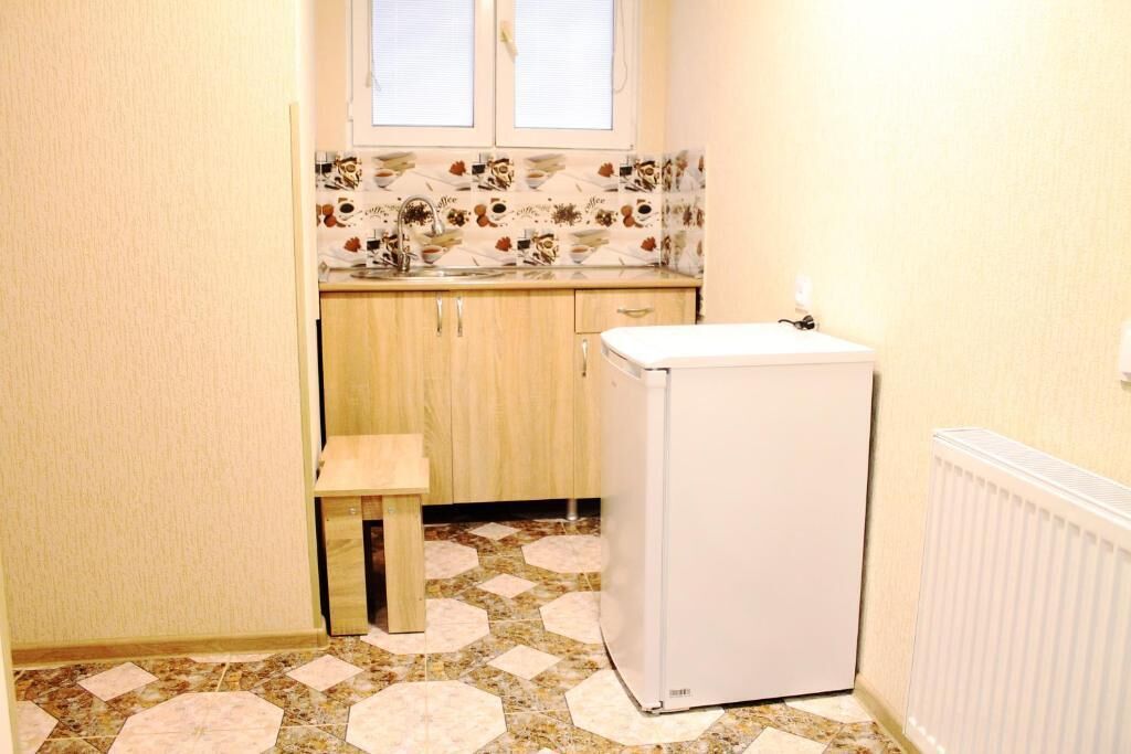 A small kitchen with a refrigerator, a sink, and a window above the countertop.