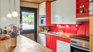 Una cocina moderna con armarios rojos y blancos, una encimera de madera y un horno empotrado.