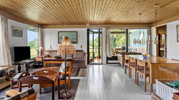 Una habitación amplia con techo de madera, un comedor y un gran ventanal que ofrece vistas al exterior.
