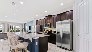Une cuisine moderne avec des meubles en bois foncé, des appareils électroménagers en acier inoxydable et un îlot central doté de tabourets de bar.