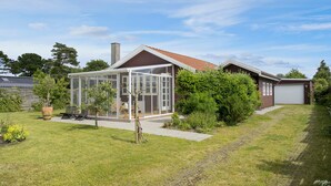 Een huis met een glazen conservatorium, een dak met rode tegels en een garage.