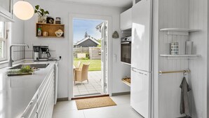 Een moderne keuken met een inbouwoven, een koffiezetapparaat en een hanglamp.