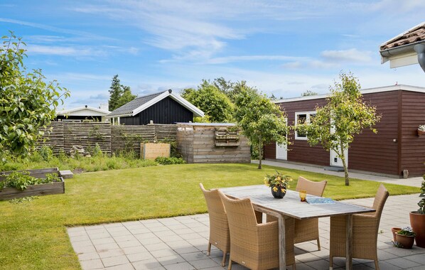 A patio with a table and chairs, a wooden fence, and a garden.