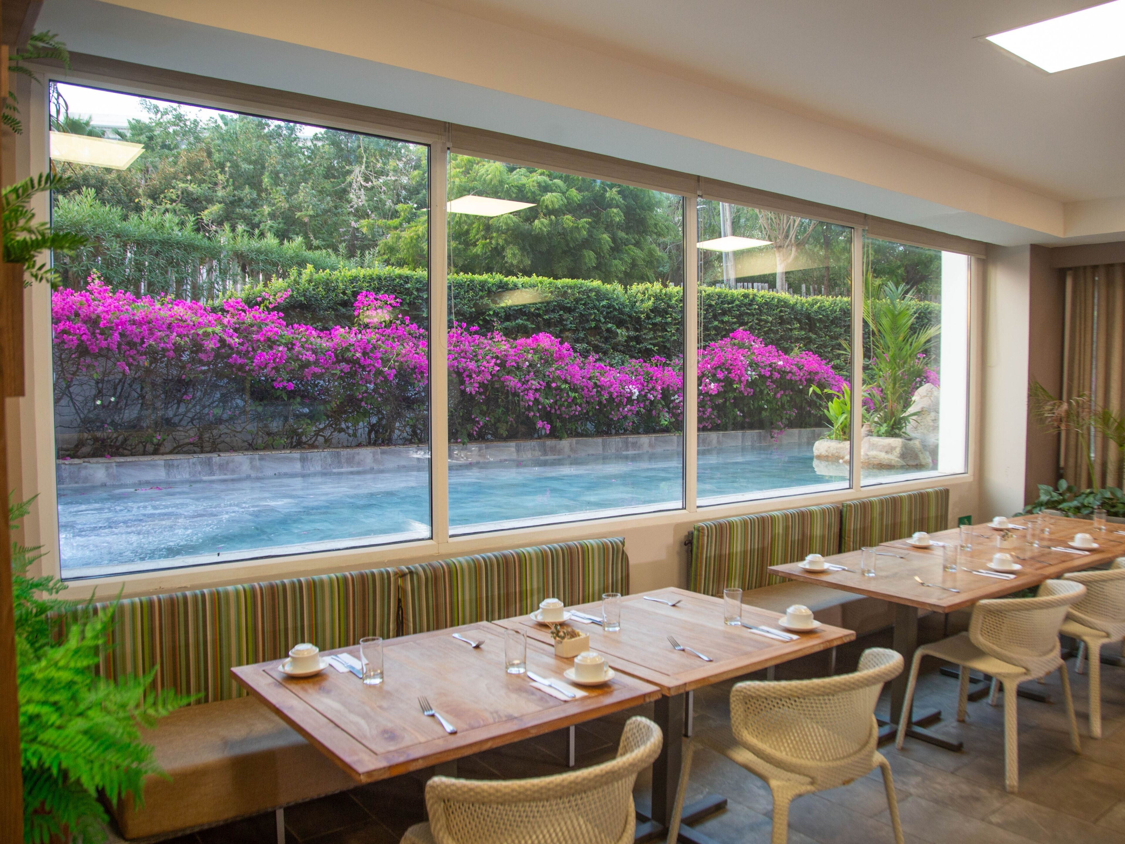 Un restaurante con amplios ventanales, mesas de madera y sillas de mimbre.