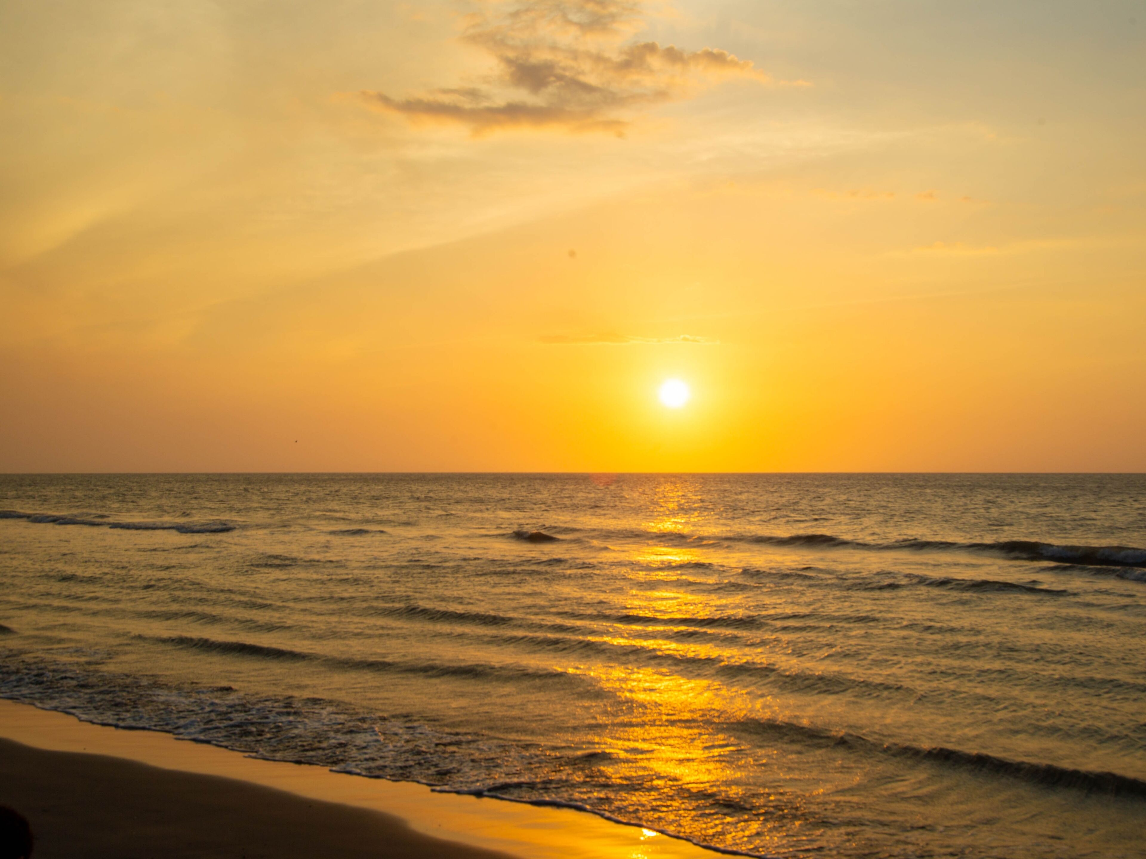 A sunset over the ocean with waves.