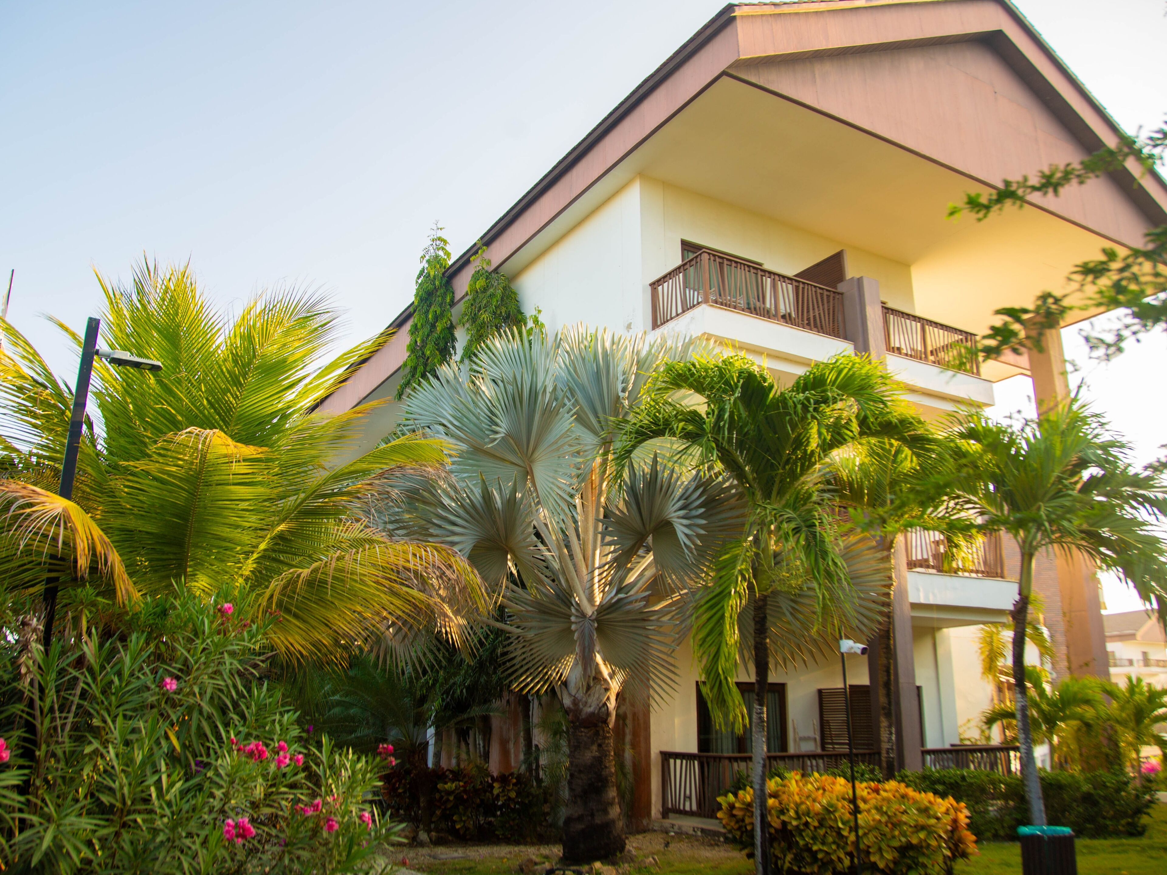 A building with a balcony, surrounded by tropical plants and flowers.