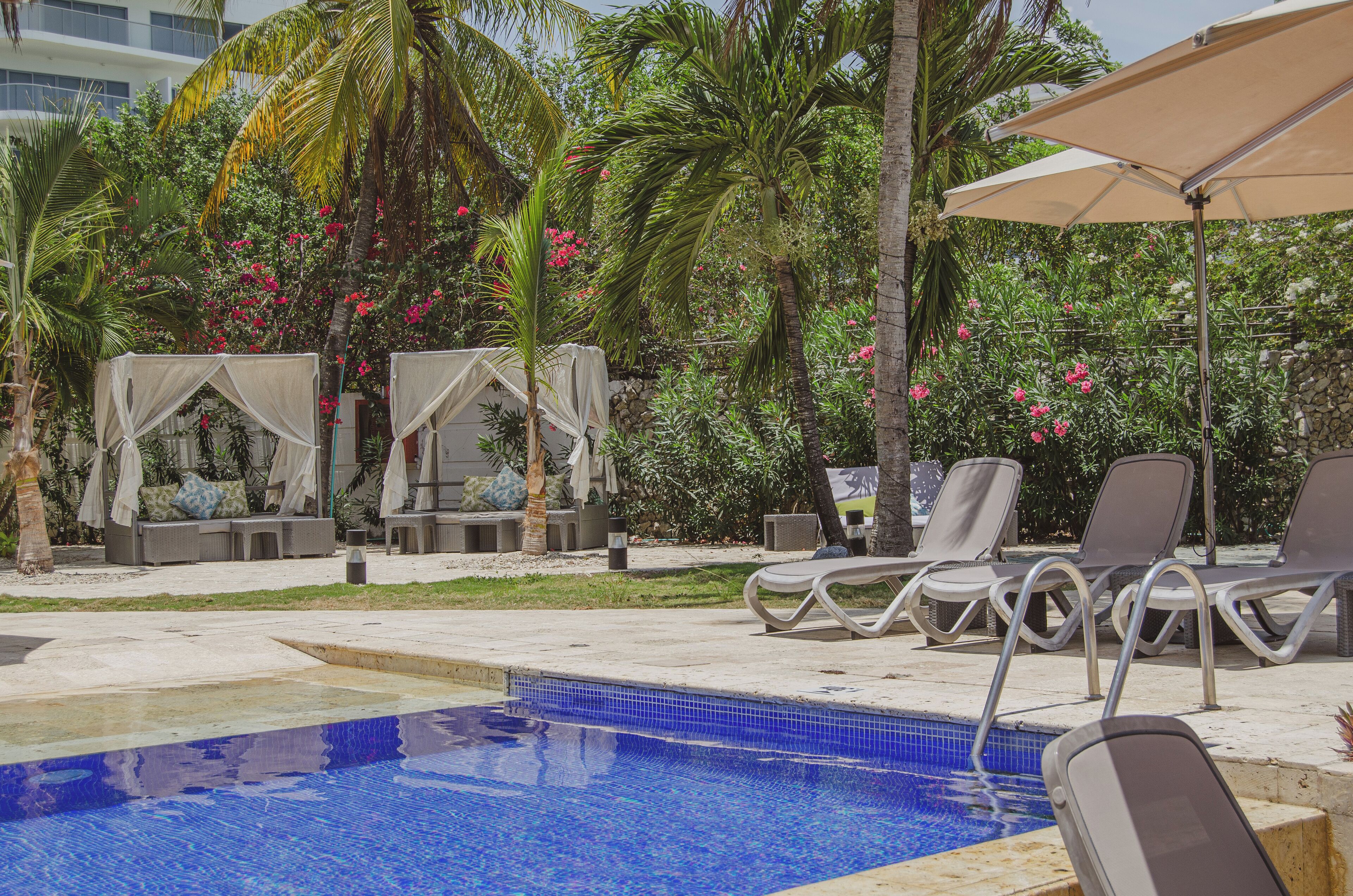 Un área de piscina con sillones reclinables y una zona de estar cubierta.