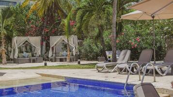 Un área de piscina con sillones reclinables y una zona de estar cubierta.
