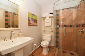 Et badeværelse med vask, toilet og brusekabine i glas.